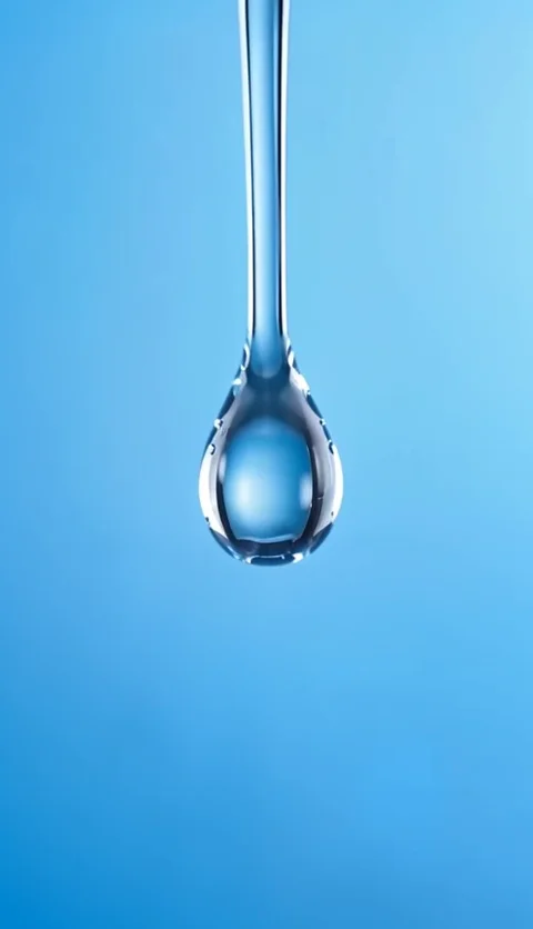 Blue skincare serum bottle with water droplets on a pale blue background